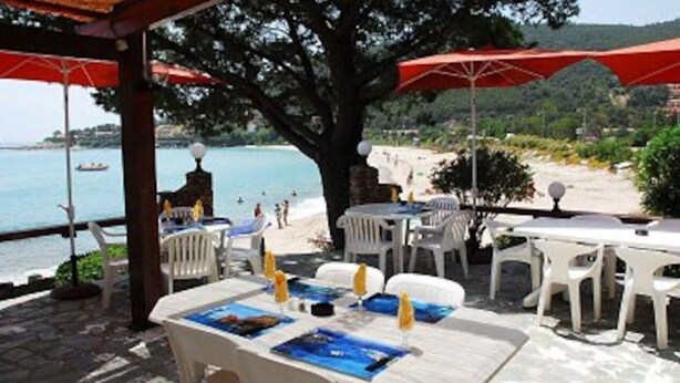 An outdoor dining area with tables and chairs, overlooking a beach and the sea. - 100% Happiness superb villa with sea view near beach, idyllic setting (Conca)