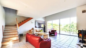 Amplia sala de estar con escalera, un sofá rojo y una chimenea.