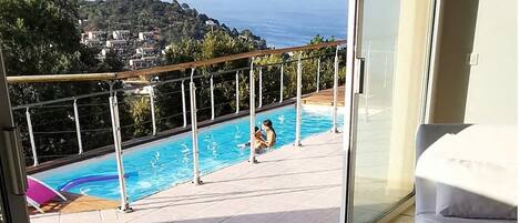 A balcony with a pool overlooking a coastal area.