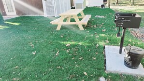 A grassy outdoor area with a wooden picnic table and a barbecue grill. - Private Studio Apartment In Lewes (Lewes)