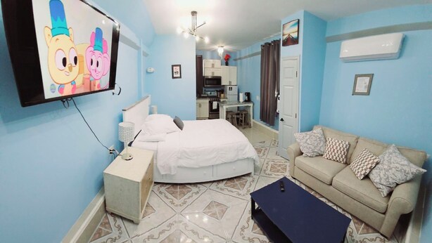 A bedroom with a bed, bedside table, and a TV displaying cartoon characters. - Private Studio Apartment In Lewes (Lewes)
