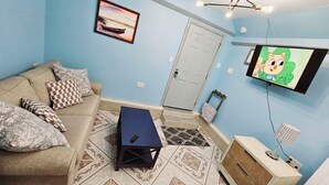 A living room with a sofa, patterned cushions, a blue coffee table, a television, and a patterned rug. - Private Studio Apartment In Lewes (Lewes)