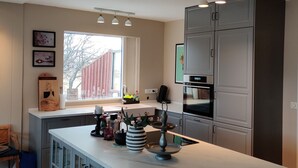 A modern kitchen with a large island, built-in cabinets, and a window providing natural light. - A farm in a stunning nature. Peace and quiet. Out of tourist traffic. (Dalabyggð)