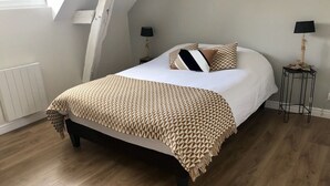 Quarto com cama, duas mesas de cabeceira, janela e radiador.