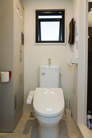 Une petite salle de bain moderne, équipée de toilettes, d’une fenêtre et d’un porte-serviettes.