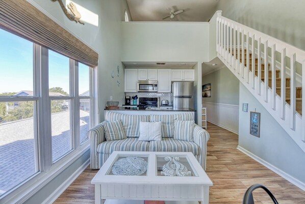 A spacious living area with a sofa, a coffee table, and a kitchen in the background.