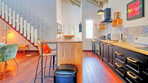 Eine moderne Küche mit einer Holzinsel, Barhocker und einer Treppe zu einer anderen Ebene.