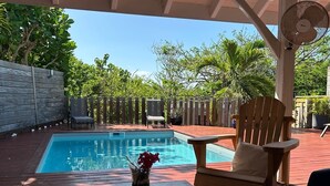 Ein Poolbereich mit Holzterrasse, einem Tisch mit Blumen und einem Stuhl.