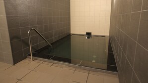 Ein modernes Badezimmer mit einer in Glas eingefassten Dusche, Wänden mit dunklen und hellen Fliesen sowie einer sichtbaren Handstange.
