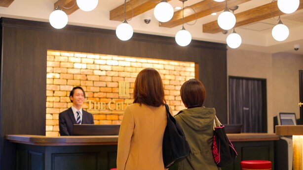 Ein Empfangsbereich mit Backsteinwand und einer Rezeptionistin.