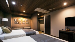 Ein Hotelzimmer mit zwei Betten, einem Fernseher, einem Kleiderständer und gerahmten Bildern an der Wand.