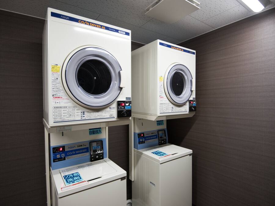 A laundry facility with two front-loading washing machines and a smaller dryer.