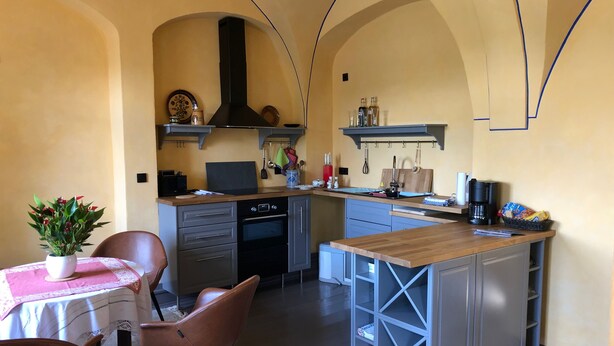 Een moderne keuken met een centraal eiland, inbouwapparatuur en een eethoek met een tafel en stoelen.