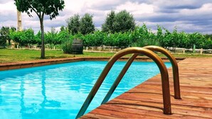 A wooden deck leading to a swimming pool with a metal ladder.