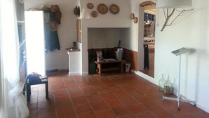 A spacious room with a tiled floor, a fireplace, and a dining area with a table and chairs.