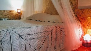 A bed with a white canopy and a crocheted bedspread.