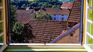 A view from a window overlooking a village with terraced houses and green fields. - Stylish elevated village house with stunning countryside views. (Frolois)