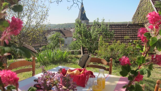 A table set outdoors with a bottle of orange juice, a glass, and a basket of bread. - Stylish elevated village house with stunning countryside views. (Frolois)