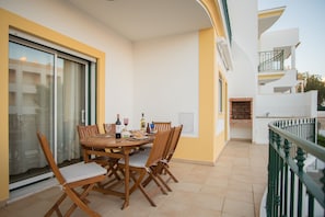 Un coin repas avec une table dressée pour quatre personnes, une porte-fenêtre coulissante et un balcon doté d’une rambarde verte.