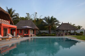 A swimming pool with lounge chairs and a thatched-roof structure.