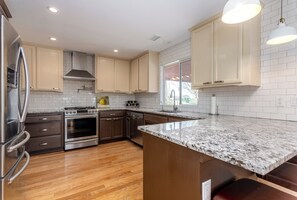 A modern kitchen with wooden flooring, stainless steel appliances, and light-colored cabinetry.