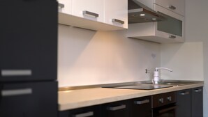 A modern kitchen with dark cabinetry, a light countertop, and a stainless steel sink. - Apartments Galboka (Mali Losinj)