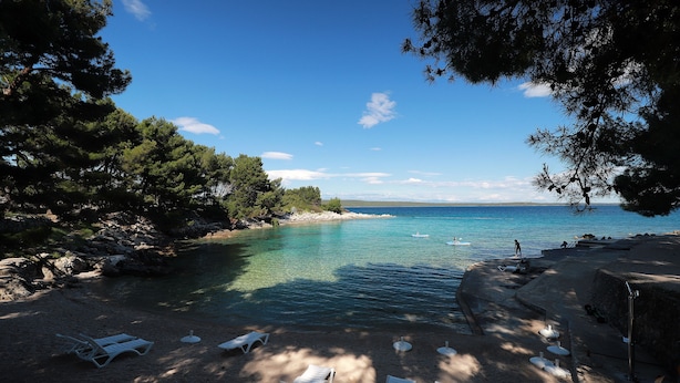 A beach with clear water, lounge chairs, and a kayak. - Apartments Galboka (Mali Losinj)