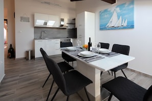 A modern kitchen with white cabinets, a stainless steel sink, and a dining area with a white table and black chairs.