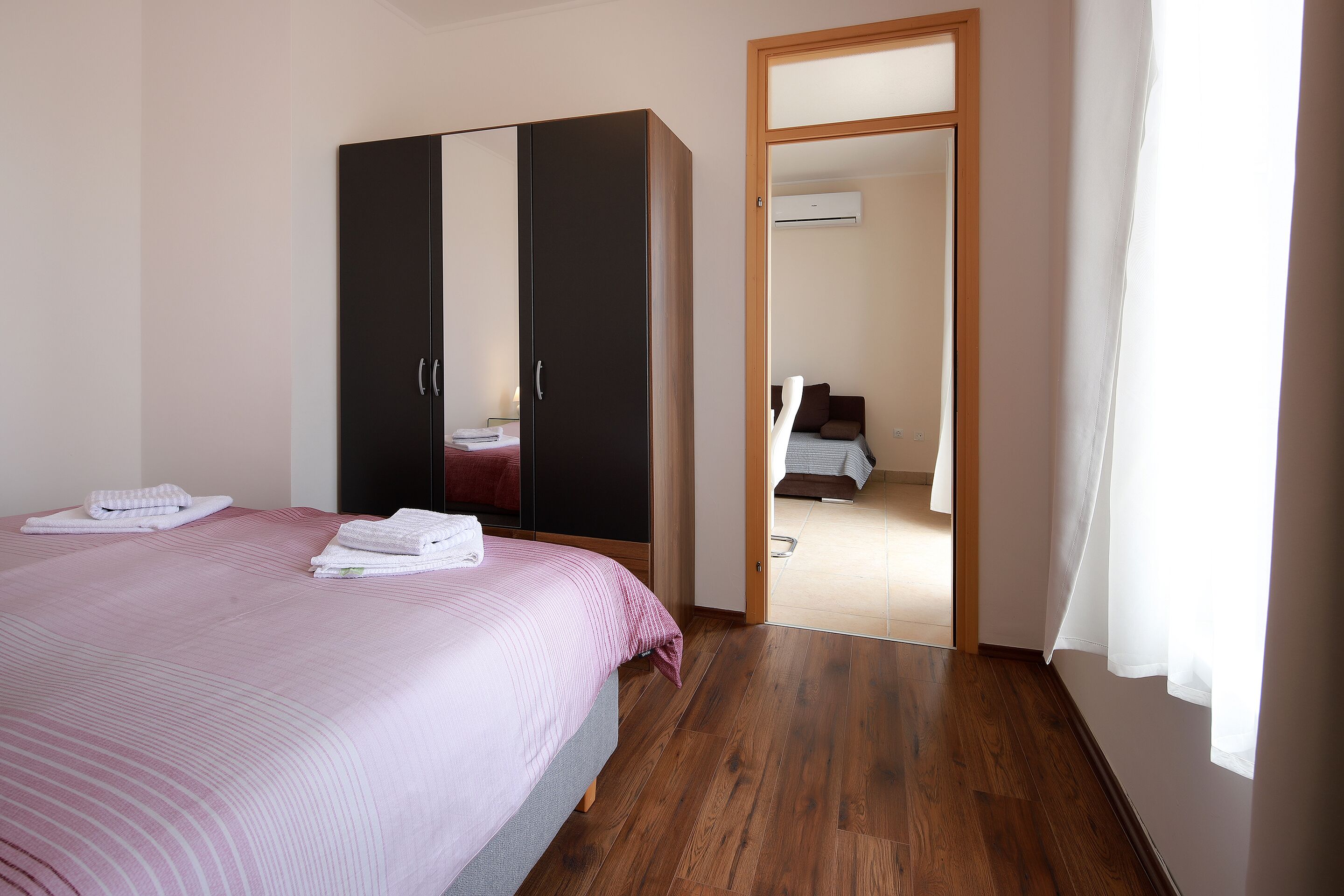 Una camera d'albergo con un letto, un armadio e una porta che dà su un'altra stanza.