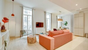 A modern living room with a sofa, a chair, a small table, and a TV. - Sweett | Turenne I - Three Bedroom Apartment, Sleeps 6 (Paris)