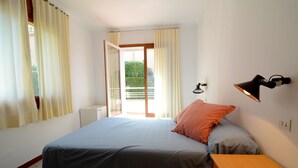 A bedroom with a bed, a bedside table, a lamp, and a sliding glass door leading to a balcony. - MIGJORN MAR PB (Estartit)