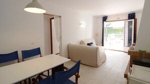 A dining area with a table and chairs, a sofa, and a view of the outdoors through a door. - MIGJORN MAR PB (Estartit)