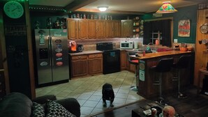 A kitchen with wooden cabinets, a refrigerator, a microwave, and a bar area with stools. - Come and enjoy some peace and quiet at the Pumpkin hollow Inn (Allegany)