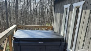 Une terrasse en bois avec un jacuzzi et deux chaises.