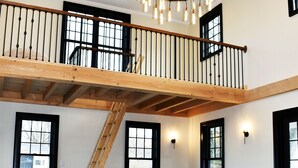 Un salón espacioso con un sofá seccional gris, una escalera de madera y una araña.