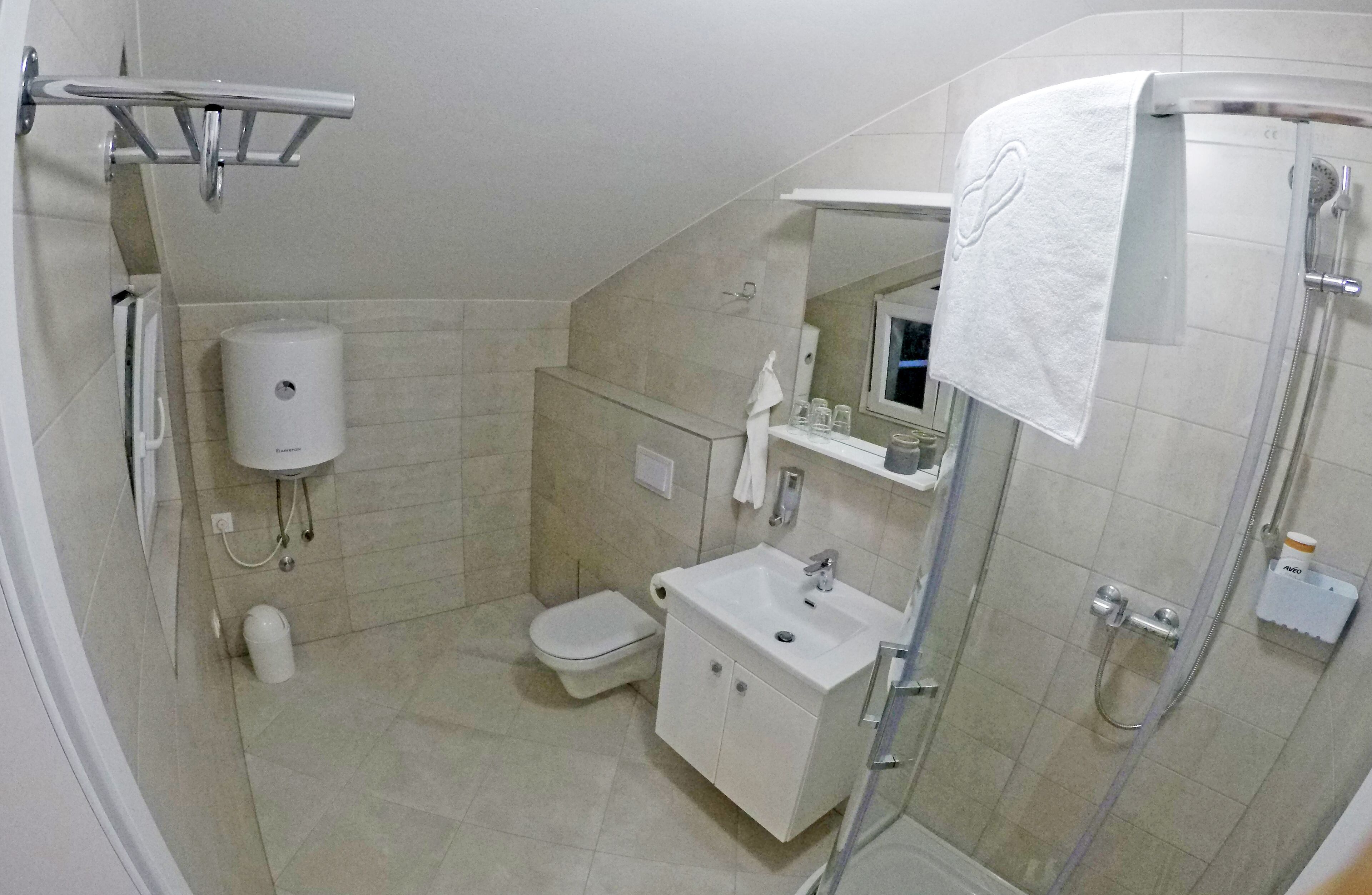 Een kleine badkamer met toilet, wastafel en douche.
