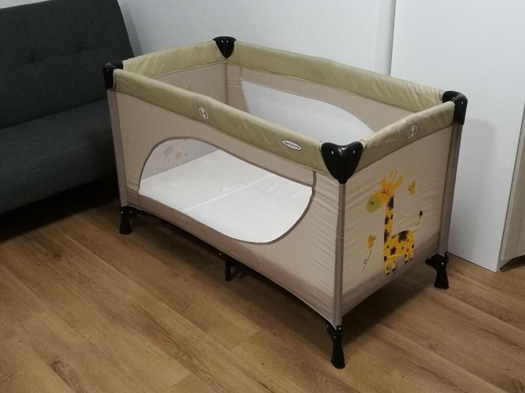 Un parc pour bébé doté d’un siège rembourré et orné d’un motif représentant une girafe sur le côté.