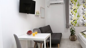 A modern living room with a white table, grey sofa, and a flat-screen TV mounted on the wall. - Guesthouse Villa DomeNico (Lozovac)