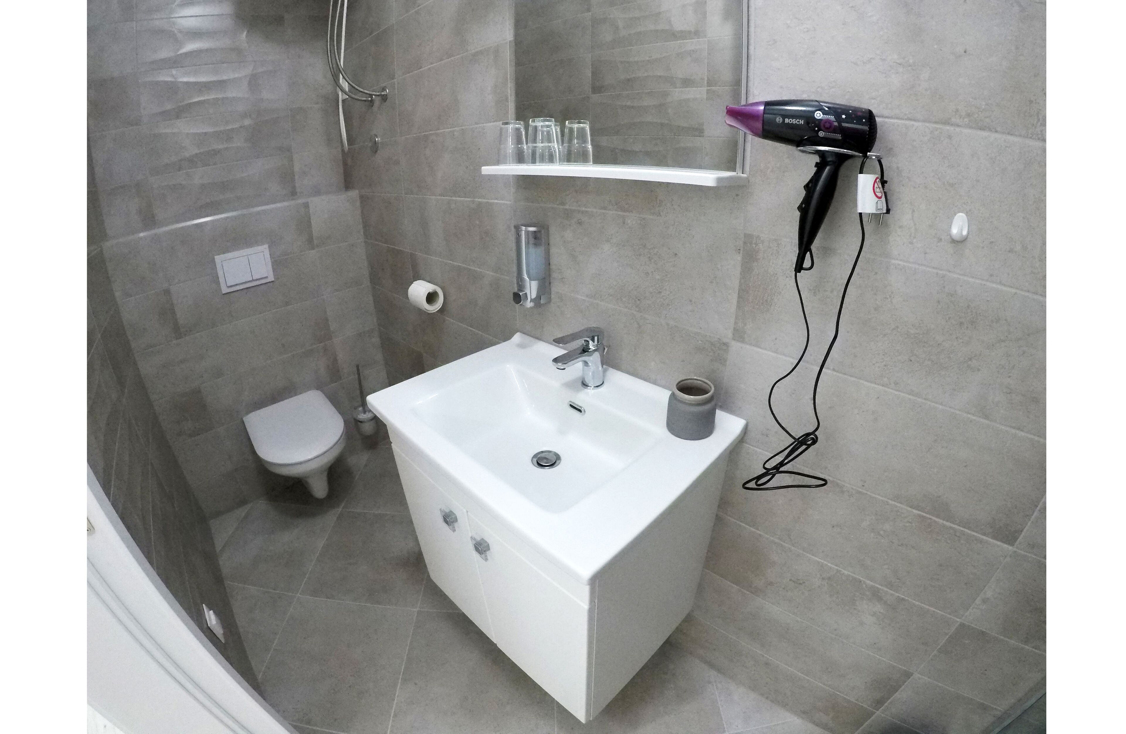 A modern bathroom with a white sink, a toilet, and a shower area.