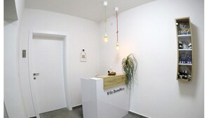 A reception desk with a sign reading "Villa DomaNico," a wooden shelf with bottles, and a potted plant. - Guesthouse Villa DomeNico (Lozovac)