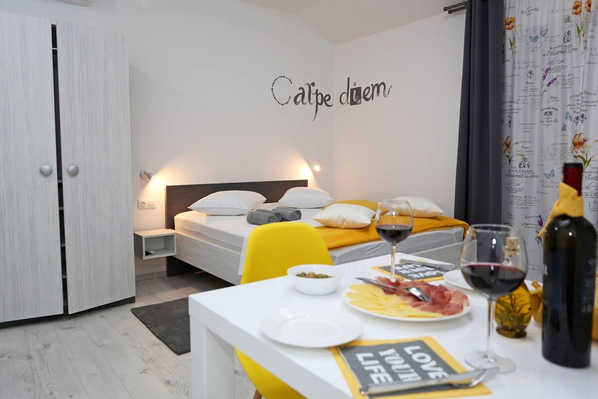 A neatly arranged bedroom with a bed, bedside table, and a wall with a motivational quote.