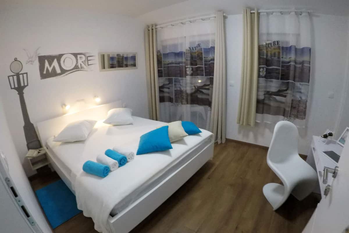A hotel room with a bed, a desk, a chair, and a window with curtains.