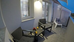 An outdoor patio with two chairs, a small table, and a fruit bowl. - Guesthouse Villa DomeNico (Lozovac)