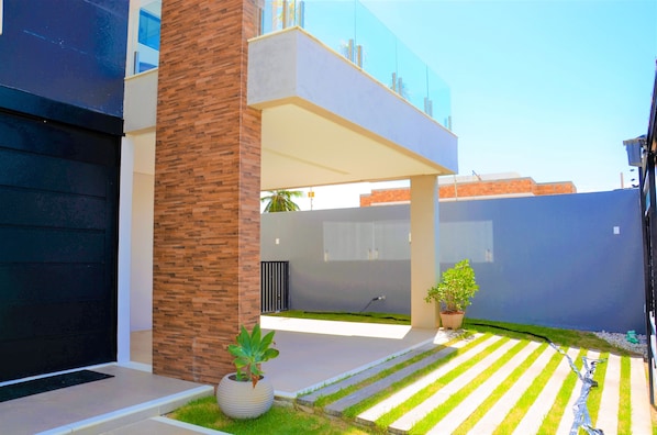 A modern house with a black garage door, a brick column, and a small garden with a striped pathway.