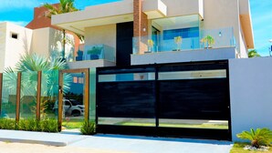 Una casa moderna de dos pisos con un amplio ventanal y una puerta de garaje negra.