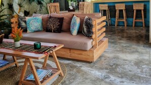 A cozy lounge area with a sofa, wooden chairs, a coffee table, and a bar area with stools.