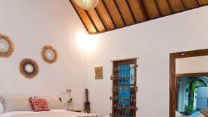 A bedroom with a large bed, a wooden ceiling, and a wall-mounted mirror.