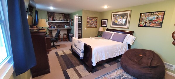 A bedroom with a bed, a desk, and a chair. There are two framed pictures on the wall.