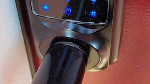 Primer plano de una cerradura de puerta con teclado numérico y mecanismo de bloqueo por botón.