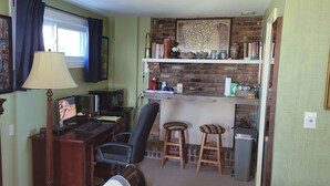 Una habitación acogedora con escritorio, silla, lámpara y chimenea de ladrillo.